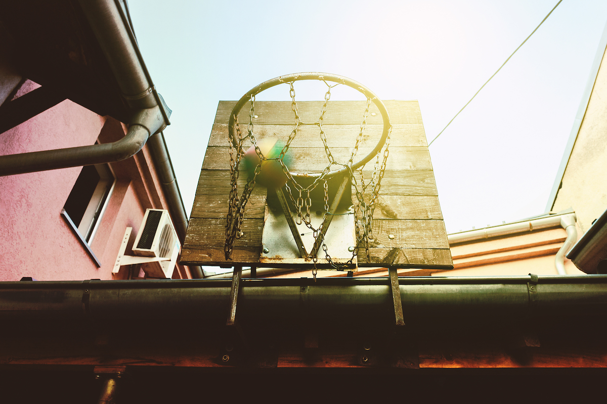 A backyard basketball hoop with the sun beaming down.