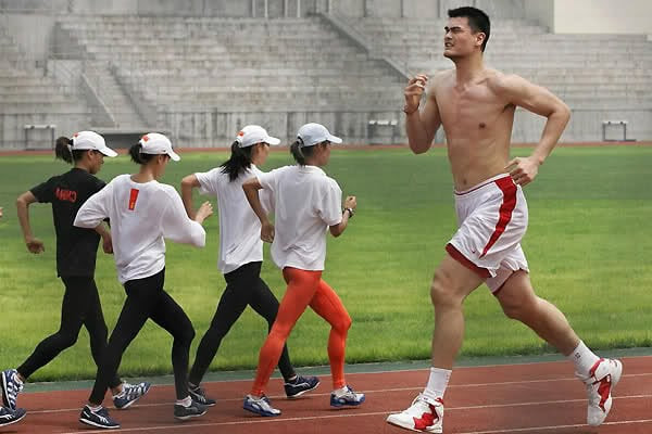 Yao Ming running around a track next to shorter women.